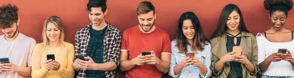 Junge Menschen mit Mitarbeiterapps auf Smartphone stehen lachend in Reihe